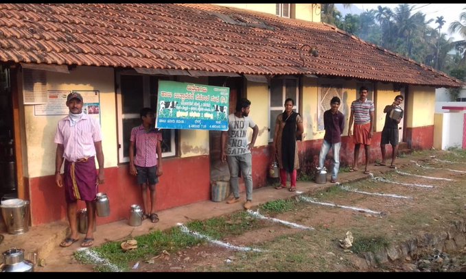 Workers maintaining distance at a milk centre in Karnataka, India.